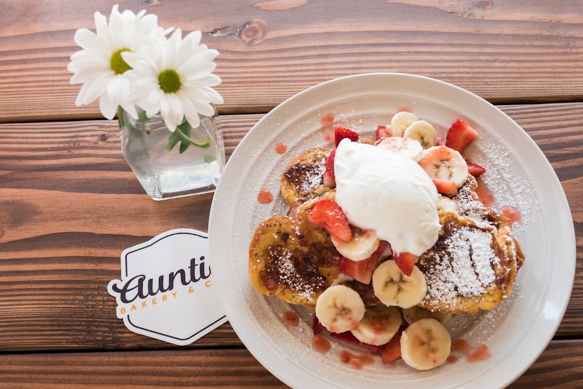 French toast with strawberries, banana and whipped cream on a white plate